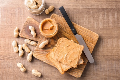 Photo of Tasty toasts with peanut butter on wooden board