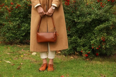 Photo of Stylish woman with trendy leather bag in autumn park, closeup