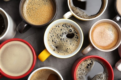 Many cups with tasty aromatic coffee on table, flat lay