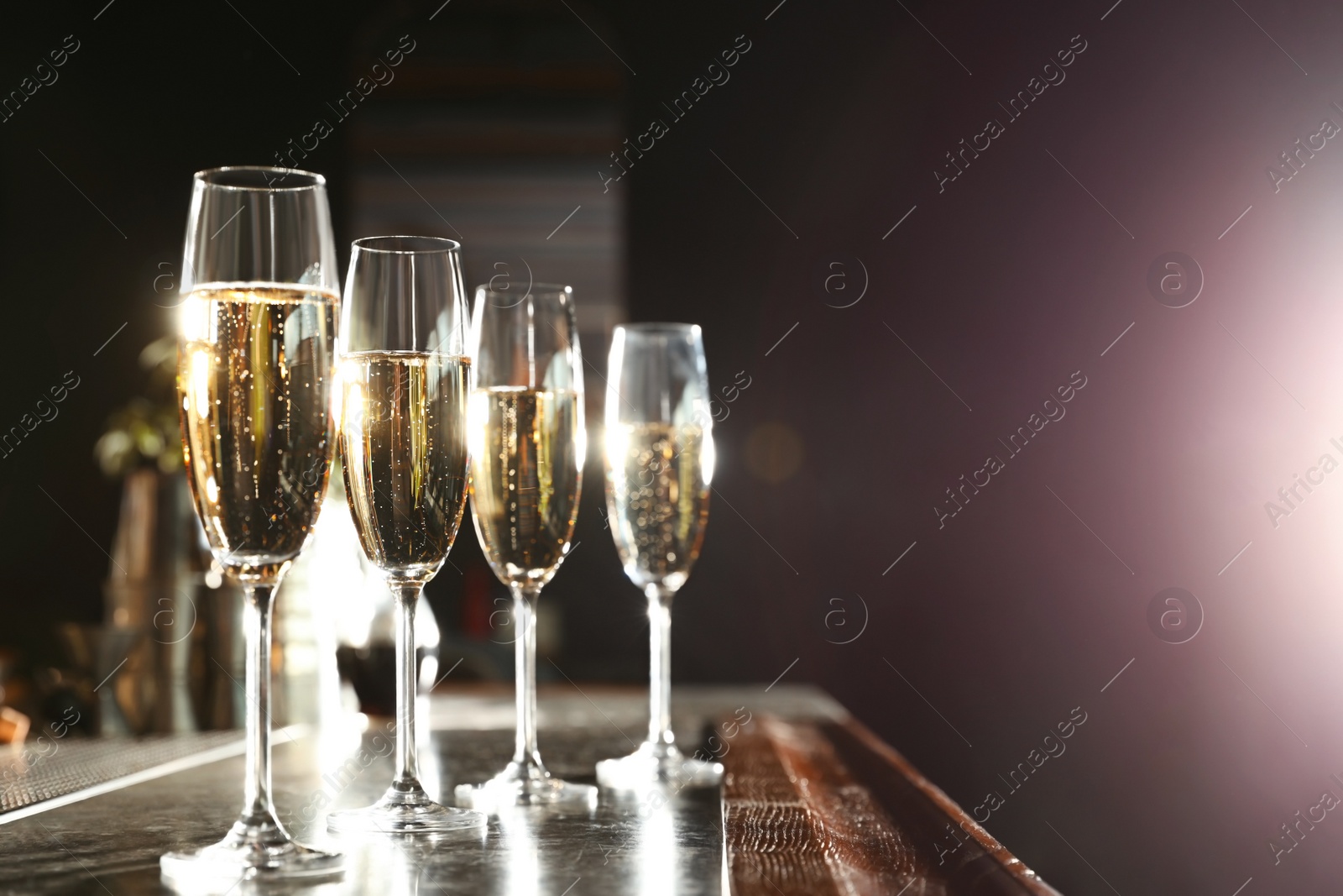 Photo of Glasses of champagne on counter in bar. Space for text