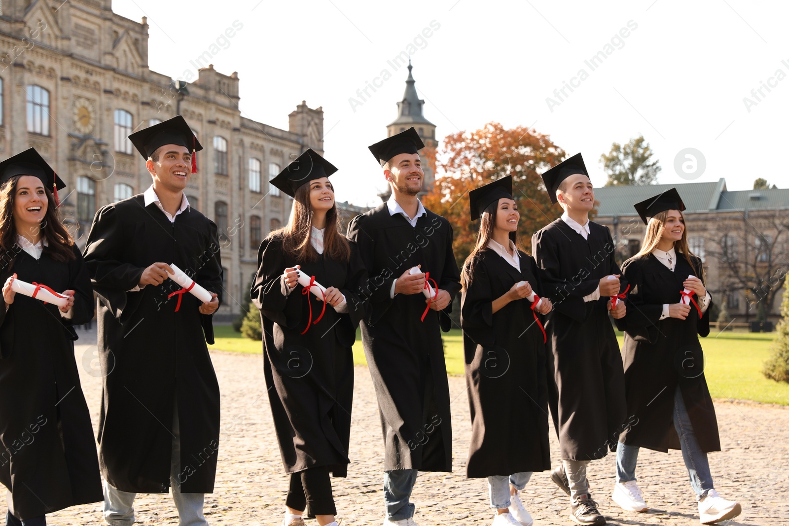 Photo of Happy students with diplomas outdoors. Graduation ceremony