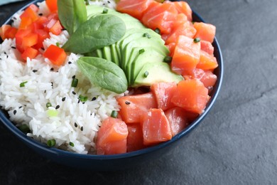 Delicious poke bowl with salmon, spinach and avocado on black table, closeup