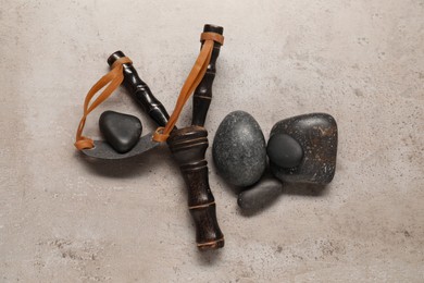 Photo of Black slingshot with stones on light grey table, flat lay