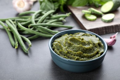 Bowl with tasty green puree and ingredients on black table