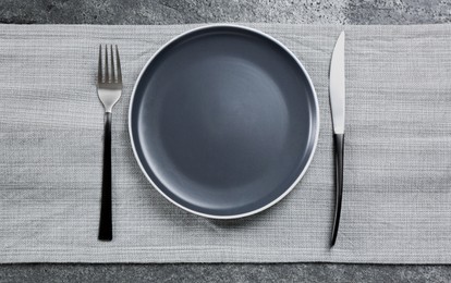 Photo of Ceramic plate, fork and knife on grey table, flat lay