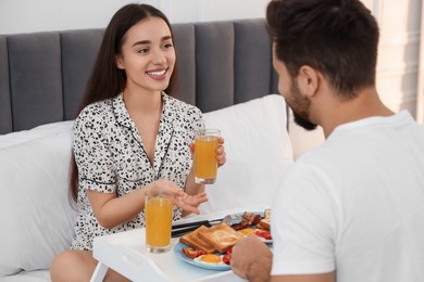 Happy couple having breakfast on bed at home