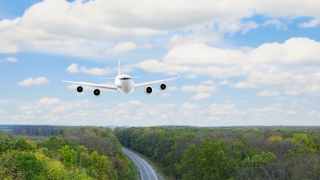 Image of Modern airplane flying in cloudy sky over wood