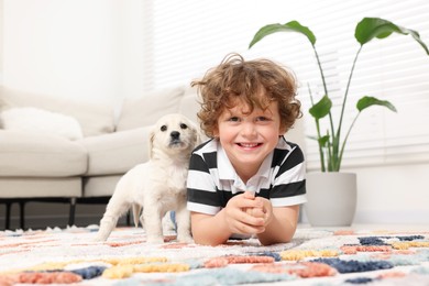 Photo of Little boy with cute puppy on carpet at home