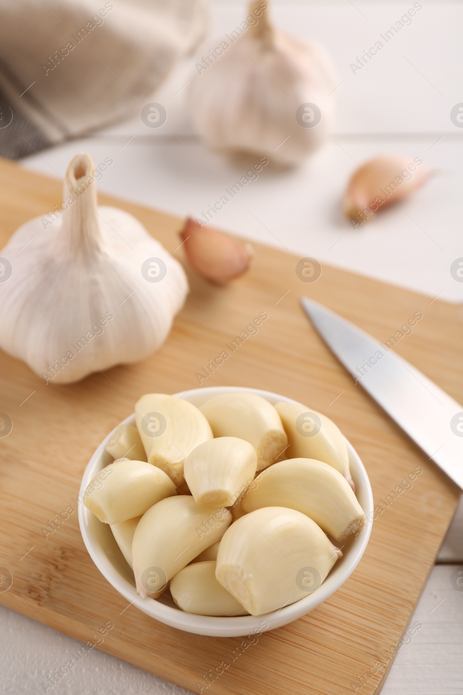 Photo of Fresh garlic and knife on white wooden table, closeup