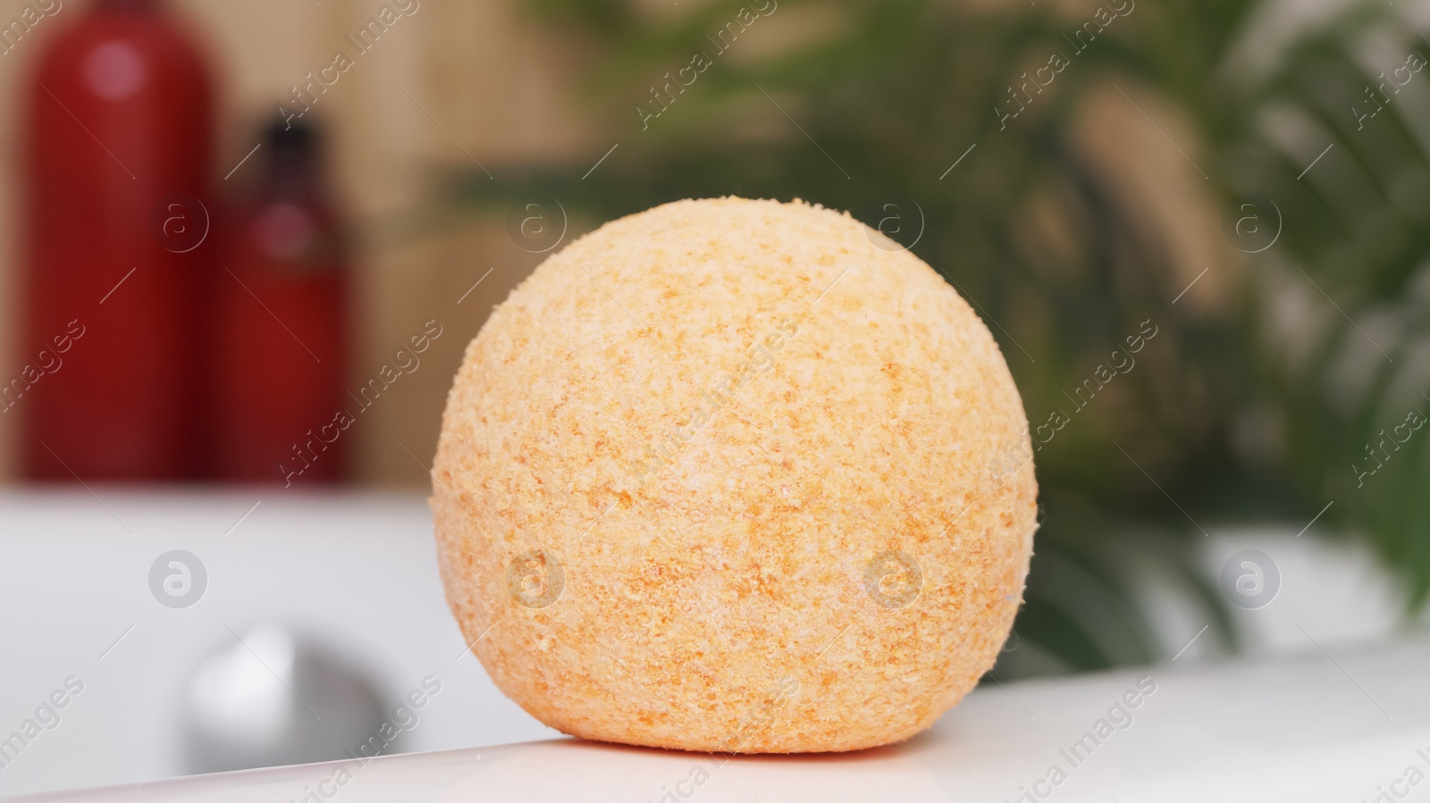 Photo of Orange bath bomb on tub indoors. Spa product