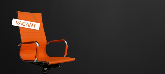 Image of Orange office chair with sign VACANT on black background, space for text. Banner design