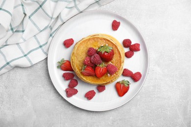 Tasty pancakes with fresh berries and honey on light grey table, top view