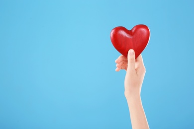 Photo of Woman holding decorative heart in hand on color background, space for text