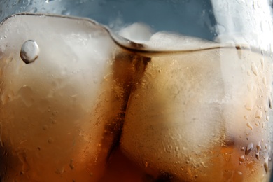 Photo of Refreshing cola with ice in glass, closeup