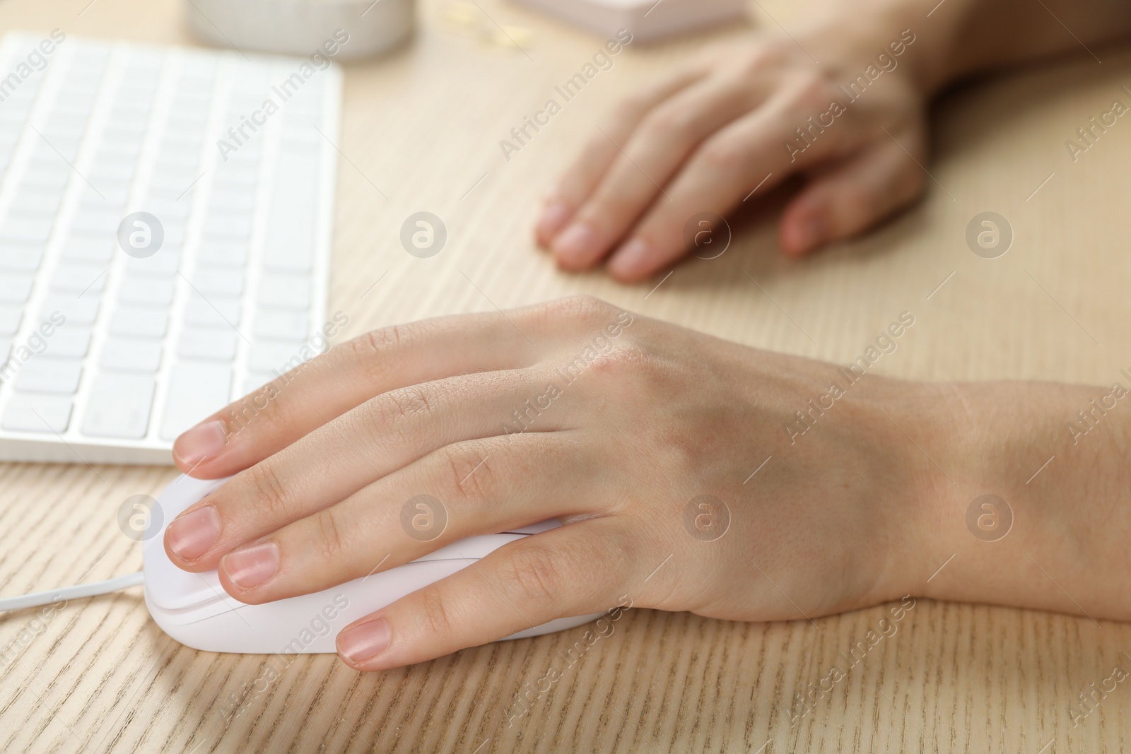 Photo of Woman using wired computer mouse at wooden table, closeup