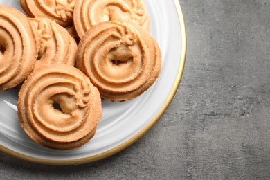 Plate with Danish butter cookies on grey background, top view. Space for text