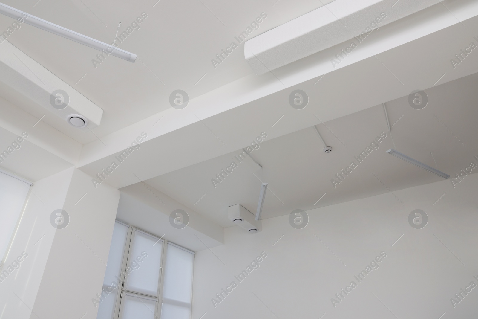 Photo of Ceiling with ventilation system and lights in room, low angle view