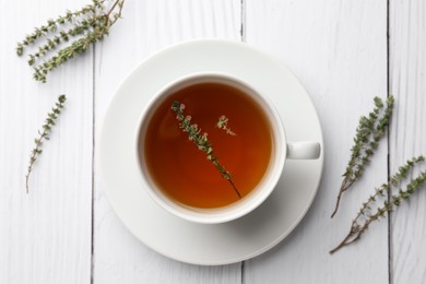 Photo of Cup of aromatic herbal tea with thyme on white wooden table, flat lay