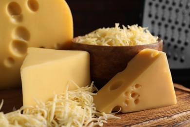 Grated and cut cheese on wooden board, closeup