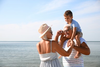 Photo of Cute little boy with grandparents spending time together near sea