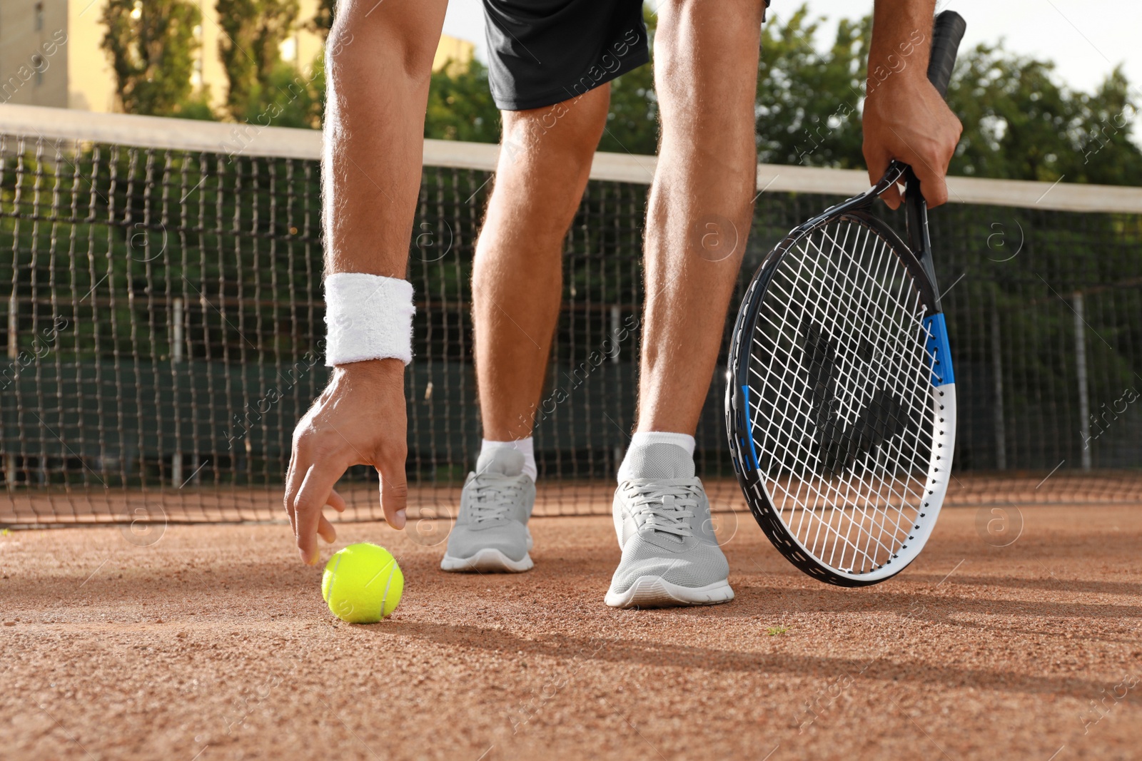 Photo of Man with tennis racket and ball at court on sunny day, closeup