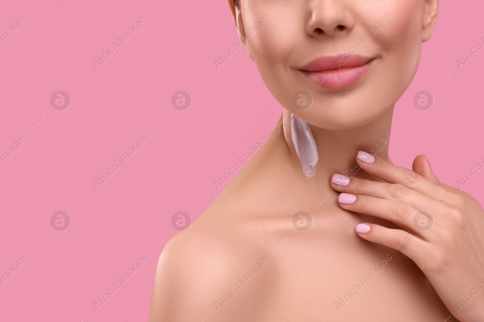 Photo of Woman with smear of body cream on her neck against pink background, closeup. Space for text