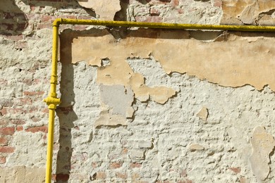 Photo of Yellow gas pipe on old brick wall outdoors