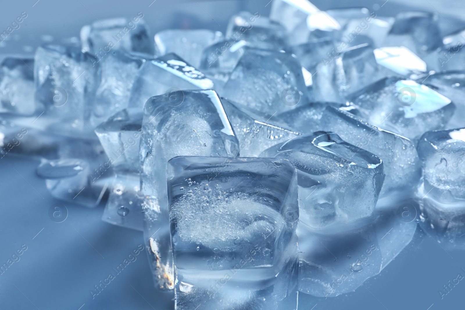 Photo of Pile of ice cubes on color background, closeup