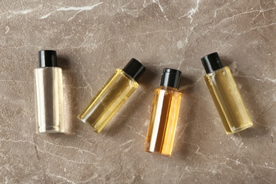 Mini bottles with cosmetic products on marble table, flat lay. Hotel amenities