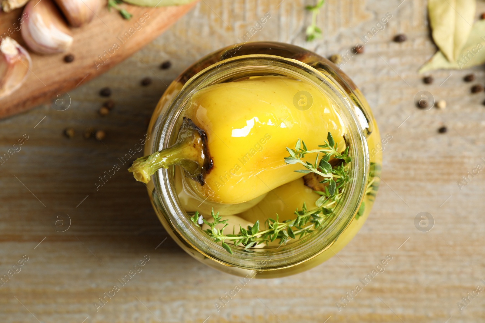 Photo of Glass jar with pickled peppers on wooden table, flat lay