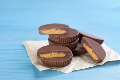 Cut and whole delicious peanut butter cups on light blue wooden table