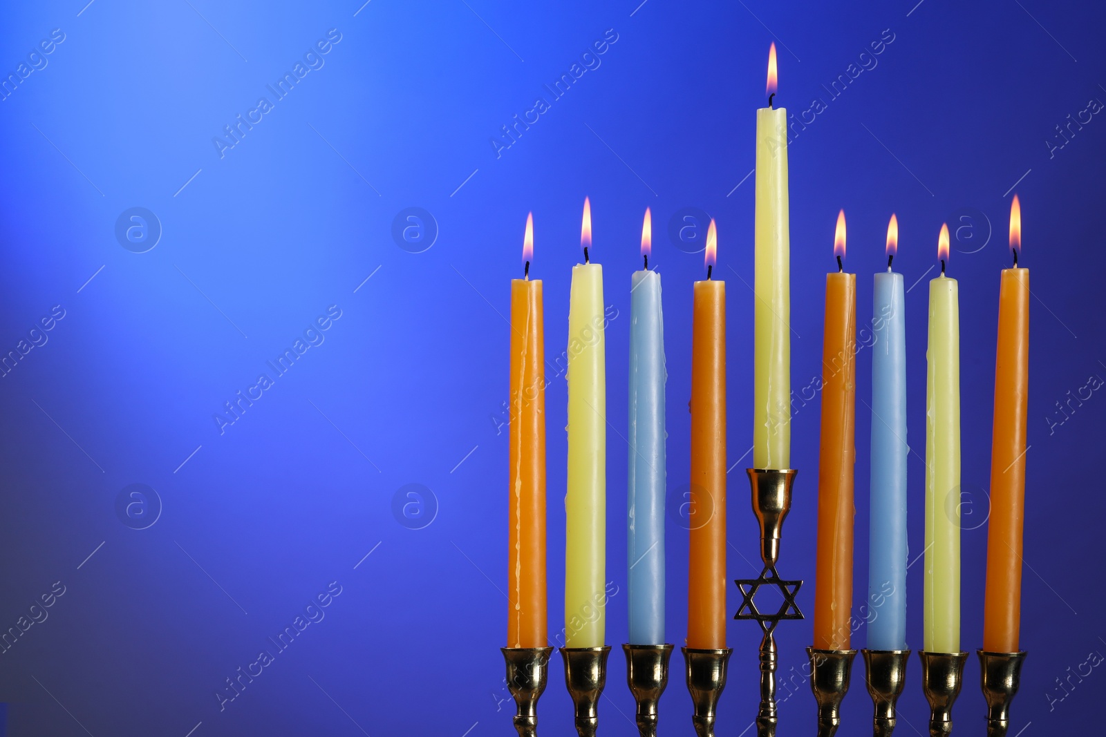 Photo of Hanukkah celebration. Menorah with burning candles on blue background, space for text