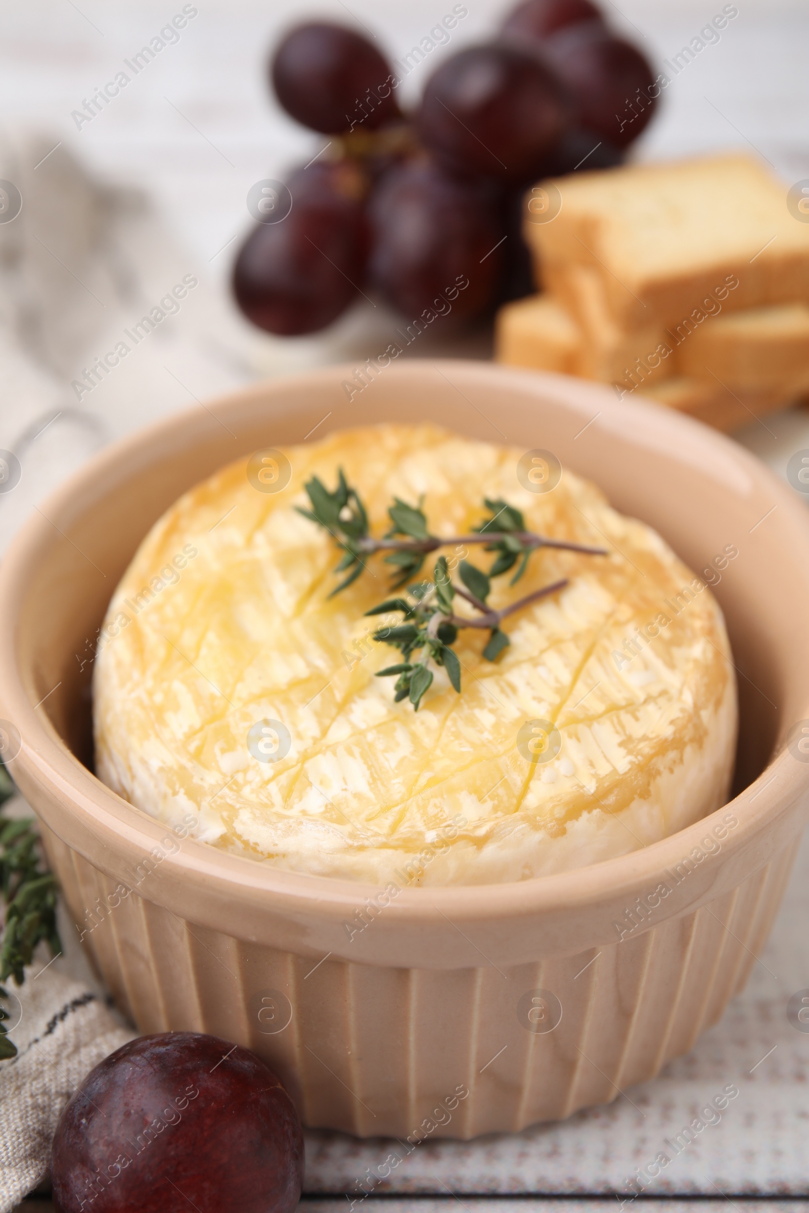 Photo of Tasty baked camembert and thyme in bowl on table, closeup