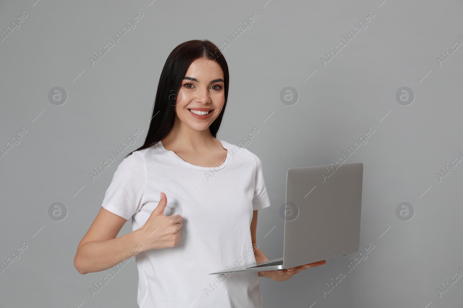 Photo of Young woman with modern laptop on light grey background