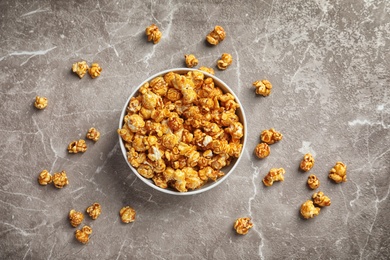 Photo of Delicious popcorn with caramel in bowl on gray background, top view