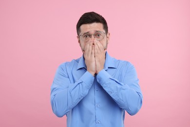 Photo of Embarrassed man covering mouth on pink background