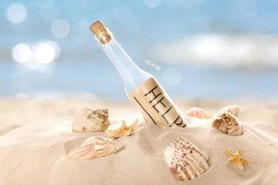 Corked glass bottle with rolled paper note and seashells on sandy beach near ocean