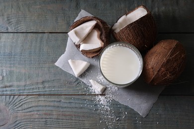 Photo of Glass of delicious coconut milk, flakes and nuts on wooden table, flat lay. Space for text