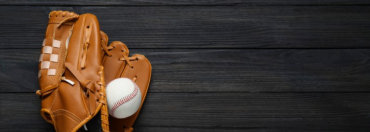 Image of Leather baseball glove and ball on black wooden table, top view. Banner design with space for text