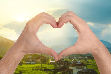 Image of Man making heart with hands outdoors on sunny day, closeup