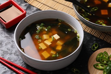 Photo of Delicious miso soup with tofu served on black textured table