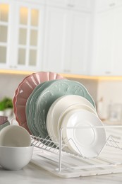 Many different clean dishware on white table in kitchen