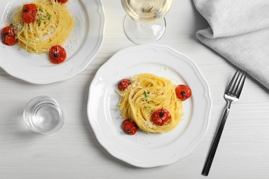 Photo of Tasty capellini with tomatoes and cheese served on white wooden table, flat lay. Exquisite presentation of pasta dish