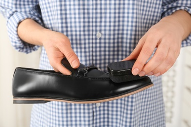 Woman cleaning stylish footwear on blurred background, closeup. Shoe care accessories