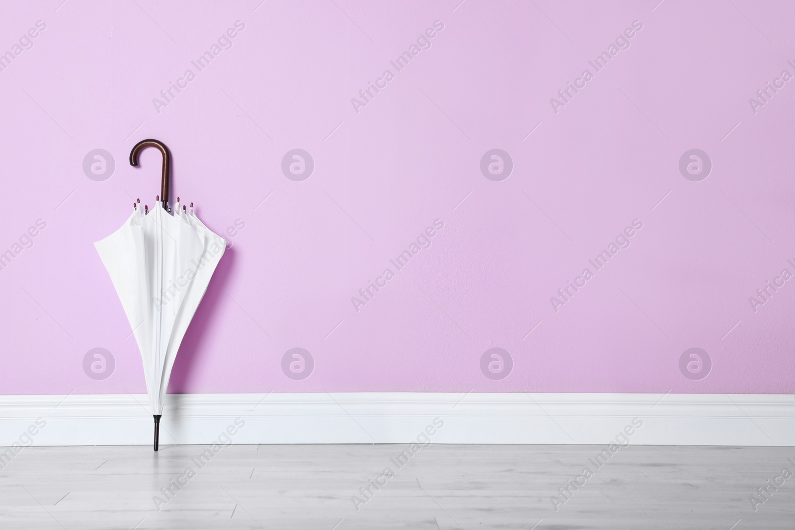 Photo of Beautiful umbrella on floor near color wall with space for design