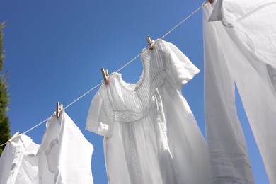 Clean clothes hanging on washing line against sky, low angle view. Drying laundry