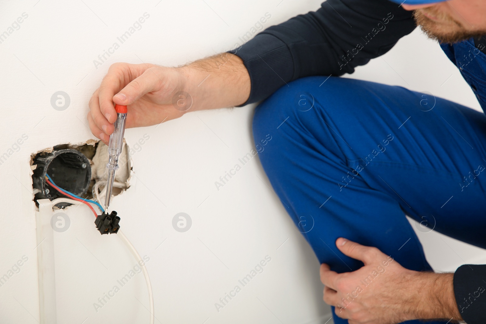 Photo of Electrician with neon-lamp tester checking voltage indoors, closeup