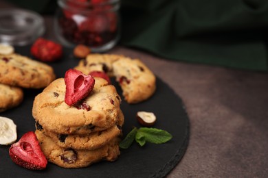 Photo of Cookies with freeze dried fruits, mint and nuts on grey table, closeup. Space for text