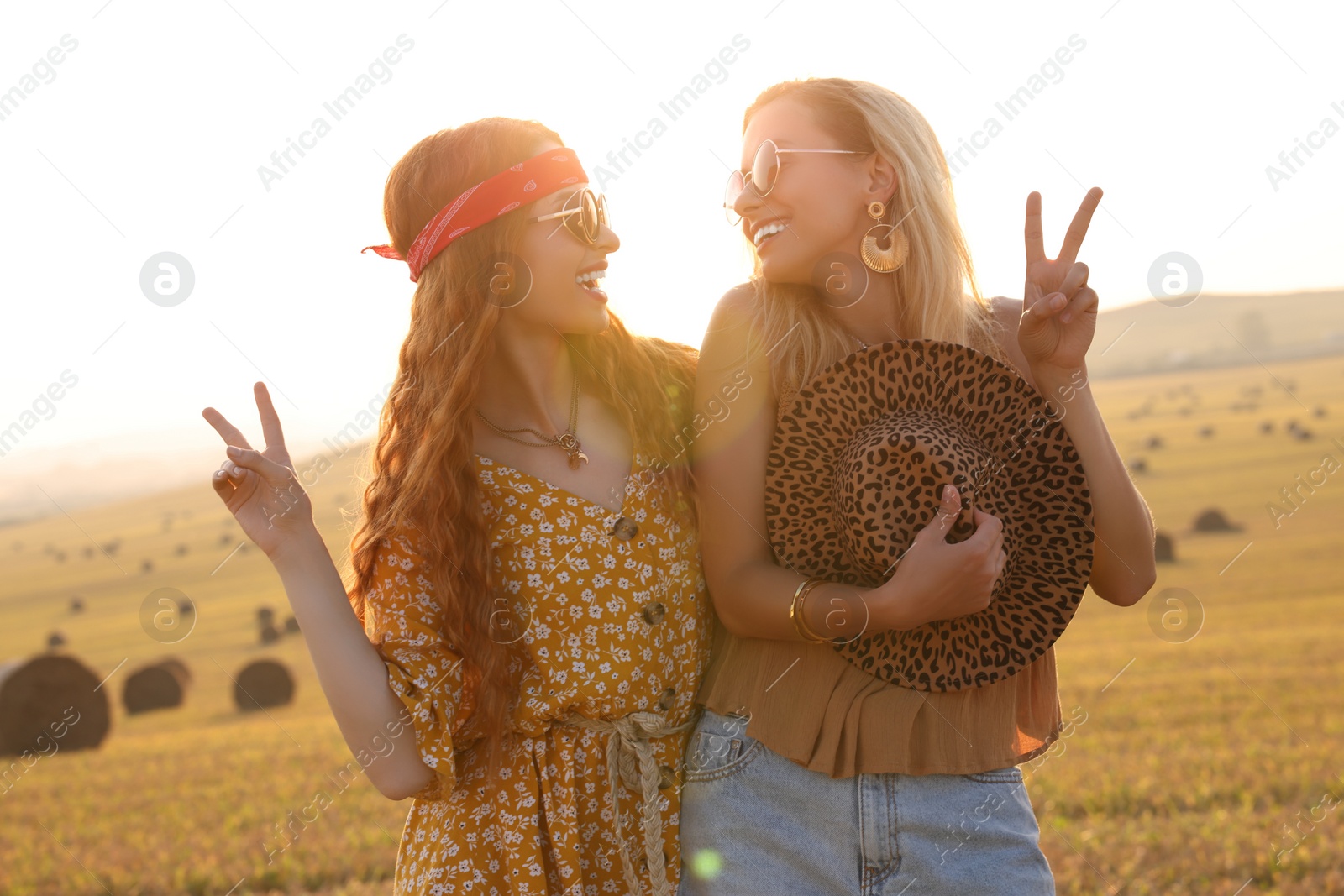 Photo of Beautiful happy hippie women showing peace signs in field