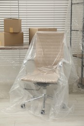 Photo of Modern furniture covered with plastic film and boxes at home